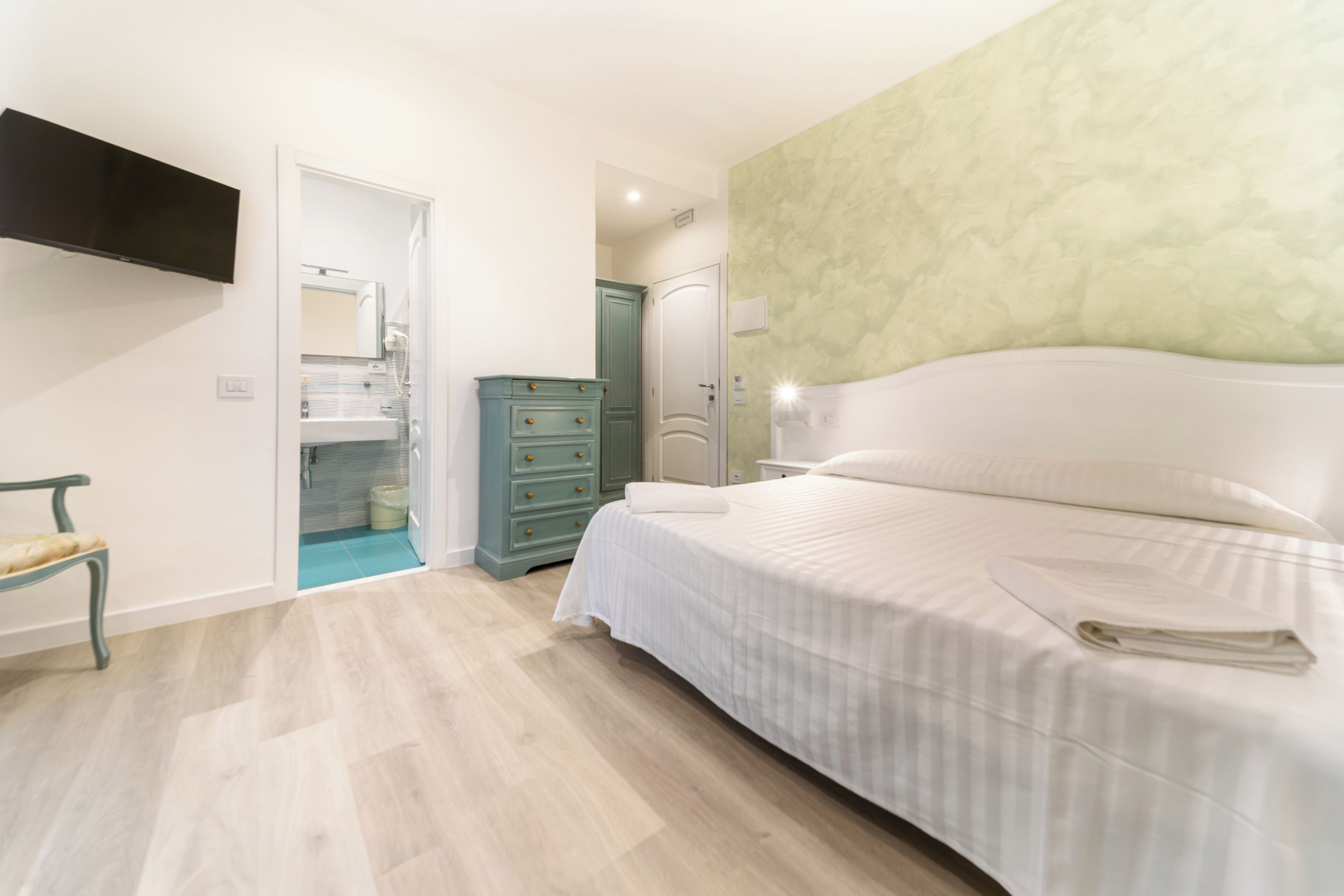 Une chambre à coucher avec un lit, une commode, un miroir et un téléviseur.