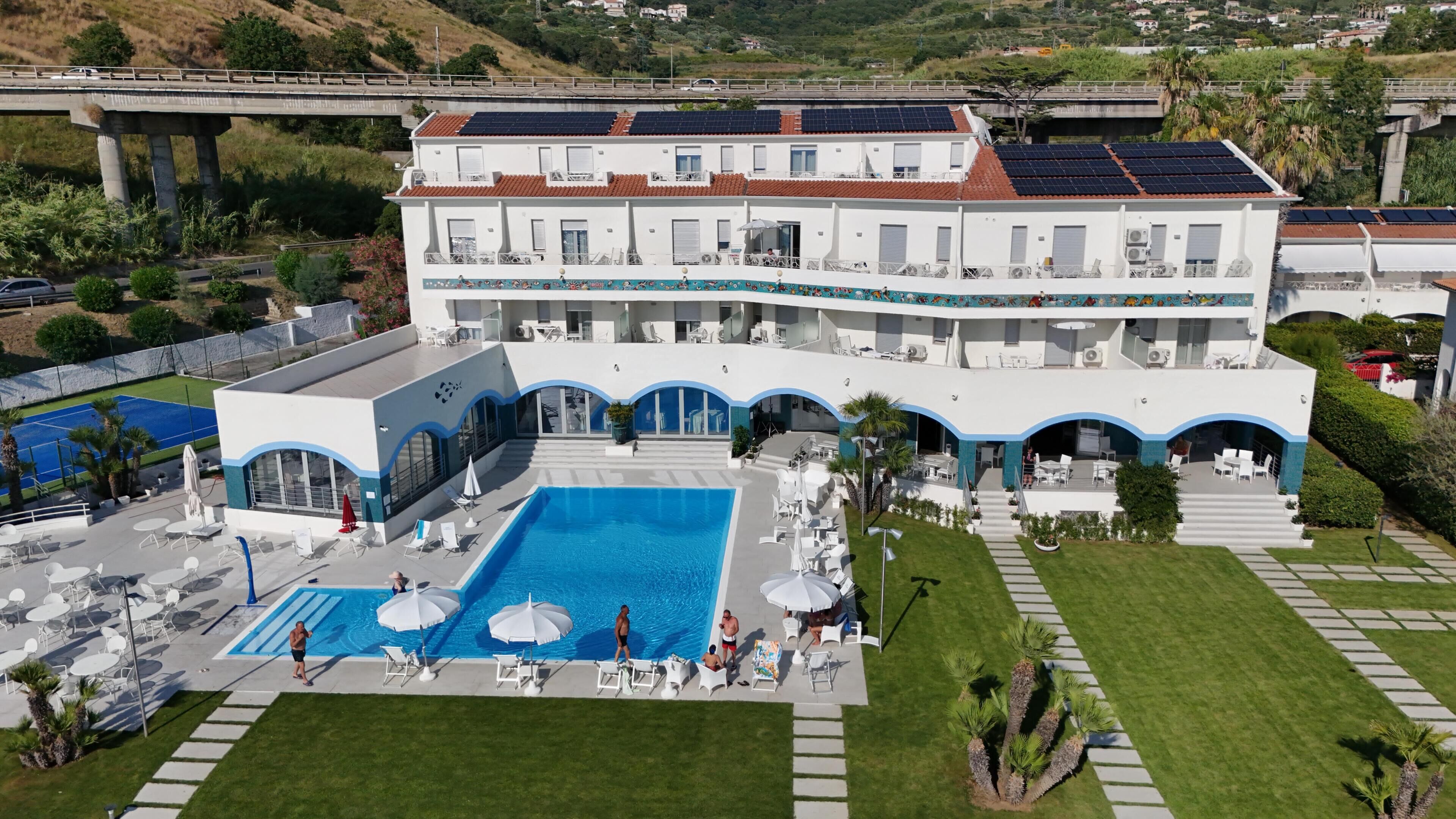 Un grand bâtiment doté d’une piscine, d’un espace extérieur aménagé et de panneaux solaires.