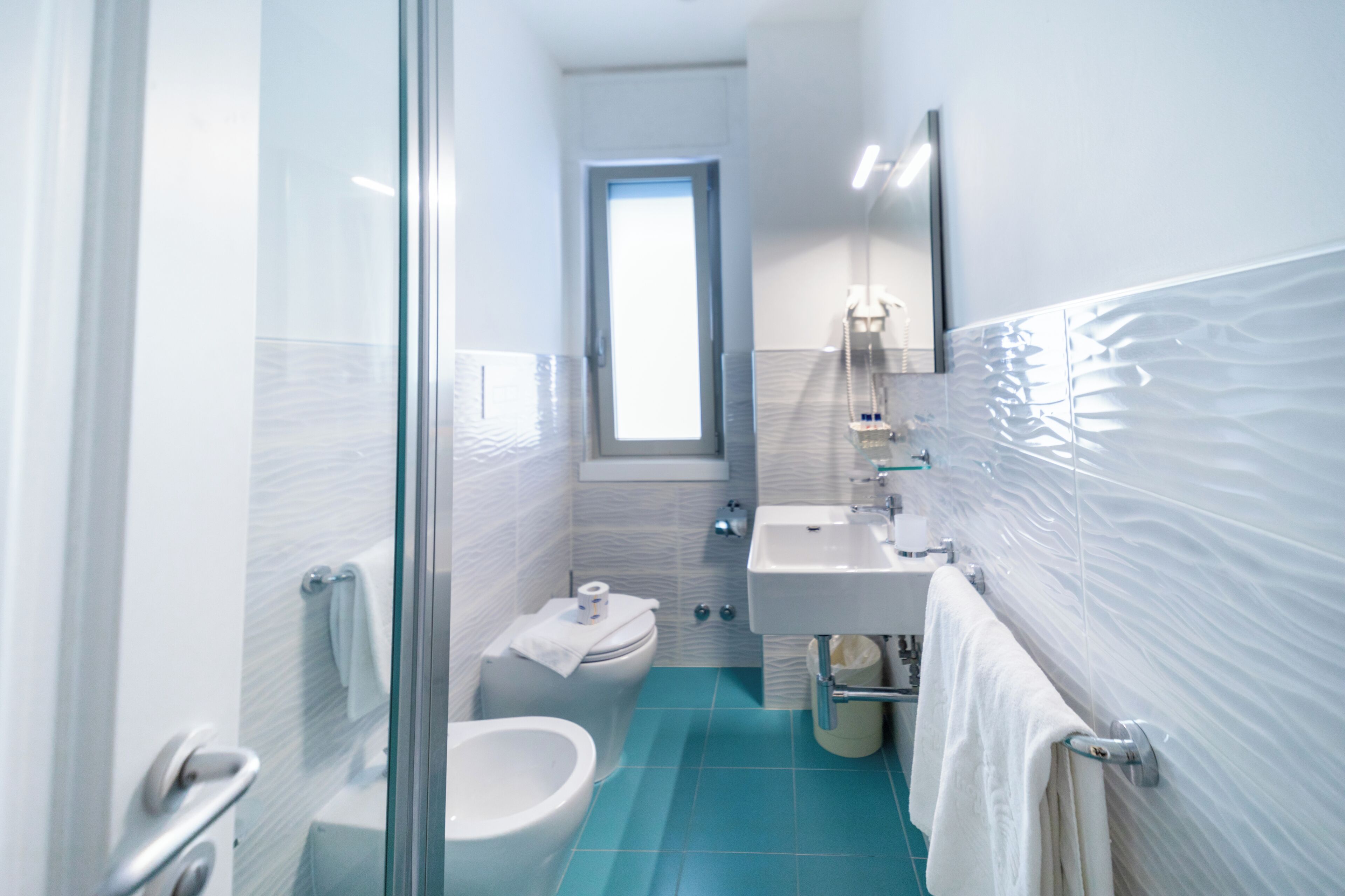 Une salle de bain moderne avec une douche à parois de verre, des toilettes, un bidet, un lavabo et un miroir.