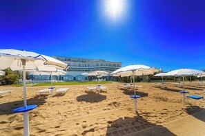 Privat strand, hvit sand, solsenger og parasoller