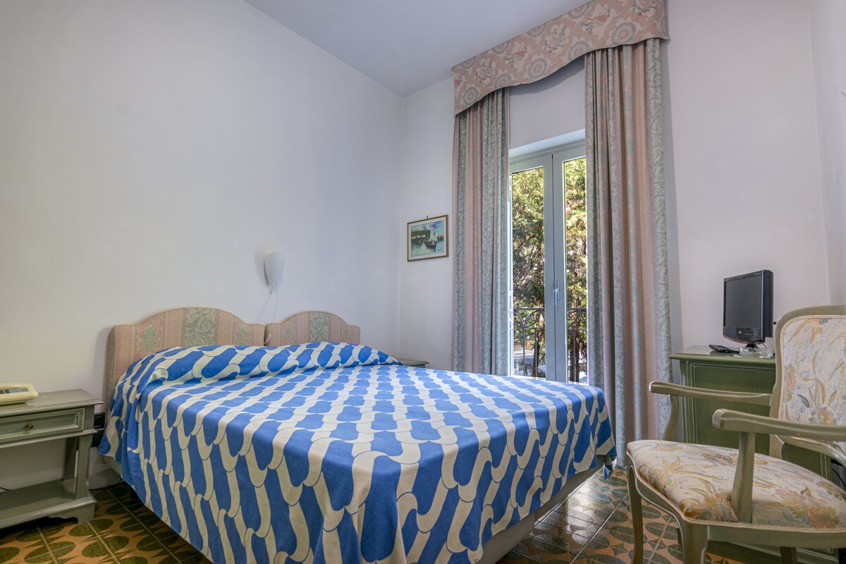 A bedroom with a bed, a chair, a desk, and a television.
