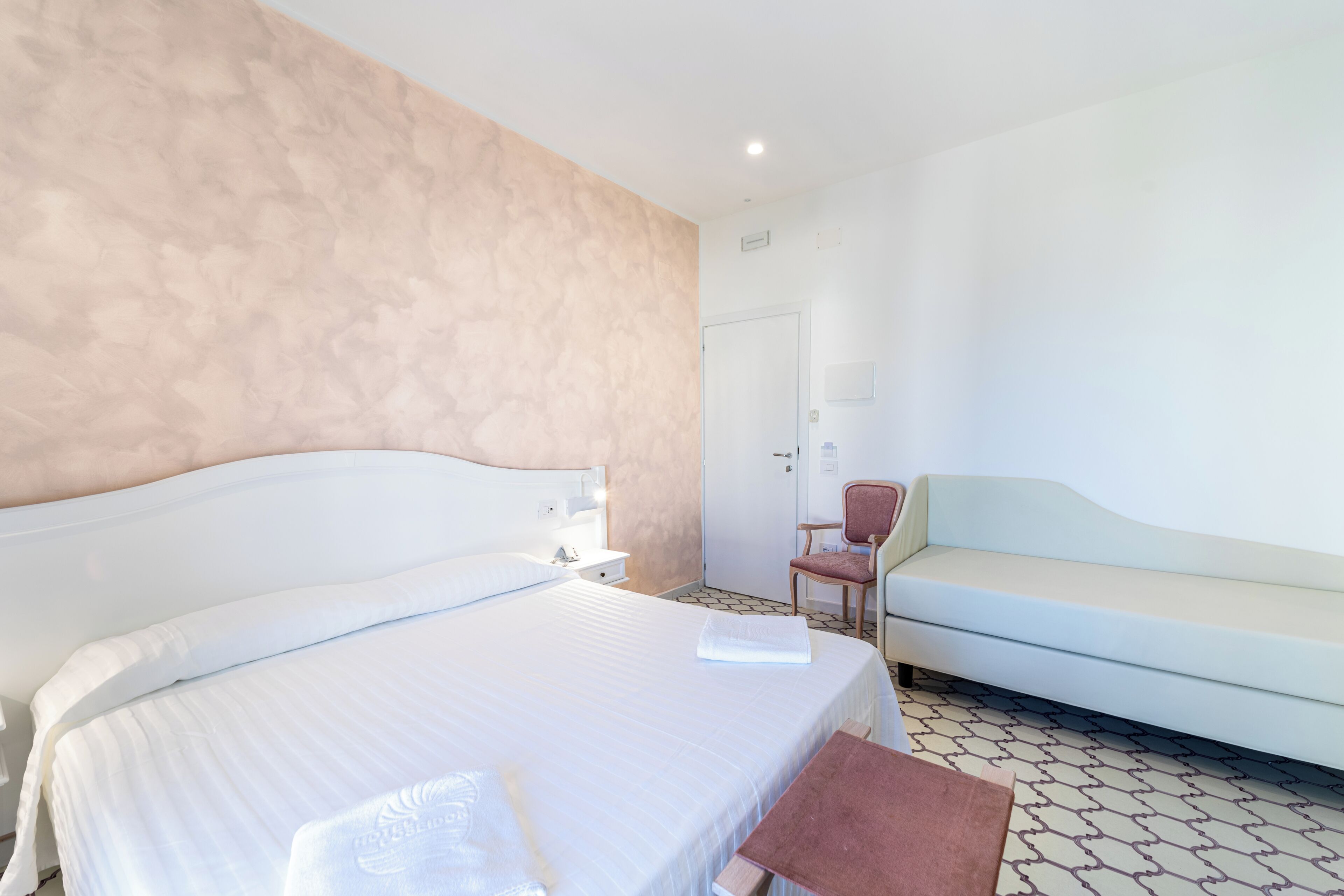 Ein Hotelzimmer mit einem großen Bett, einem Sessel, einer Couch und einer Tür.
