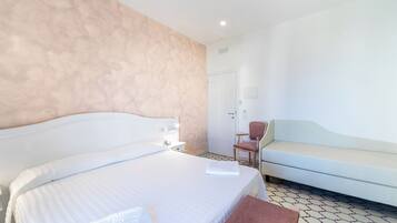 Ein Hotelzimmer mit einem großen Bett, einem Sessel, einer Couch und einer Tür.