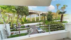 Un balcón con vista a un estacionamiento, palmeras y un puente.