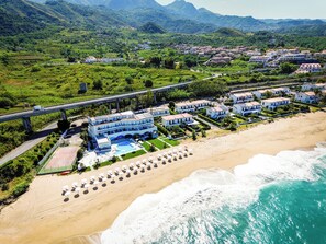 Une station balnéaire dotée d’une piscine, de parasols de plage et offrant une vue sur l’océan.