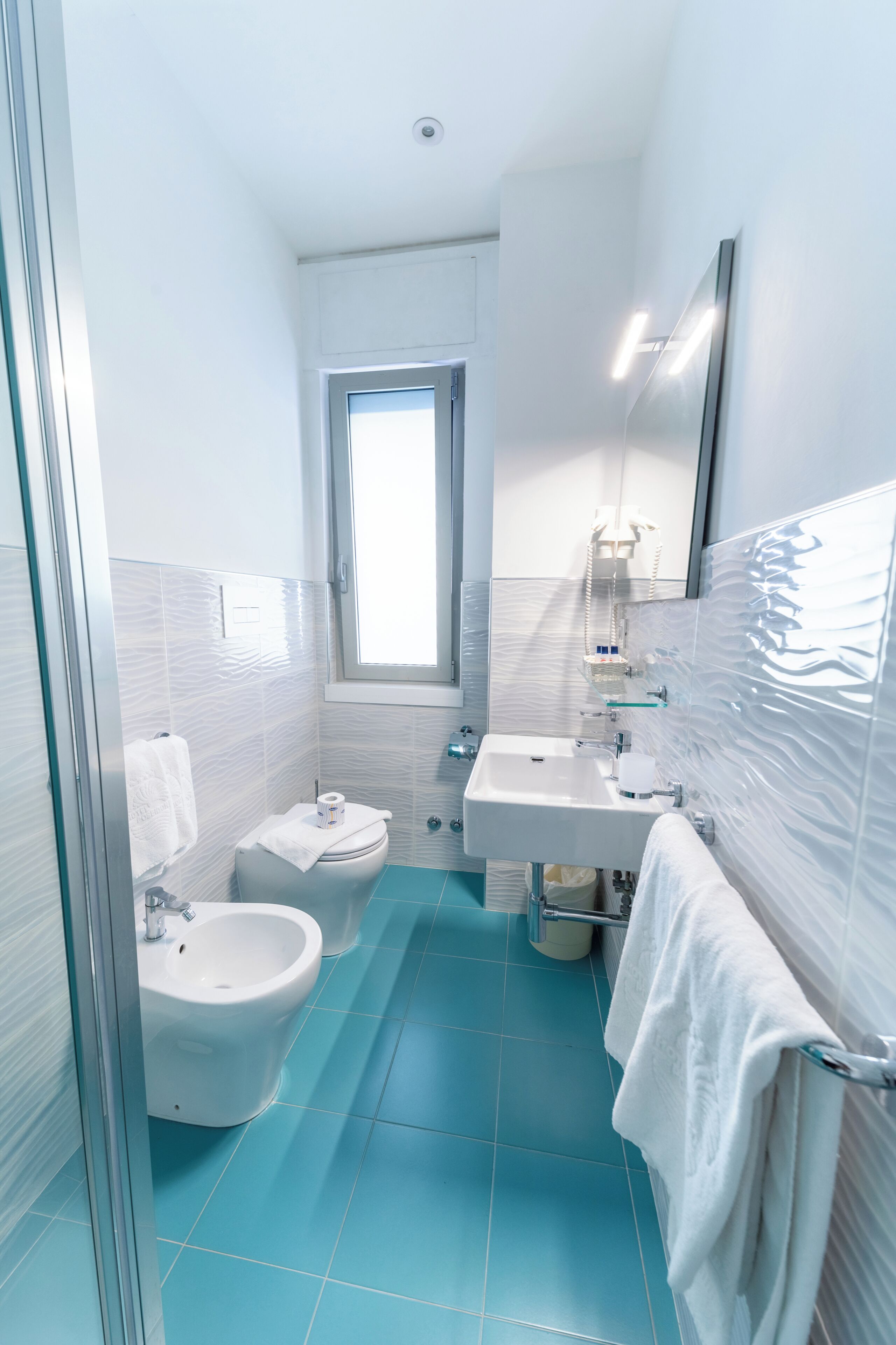 A modern bathroom with a bidet, a sink, and a mirror.