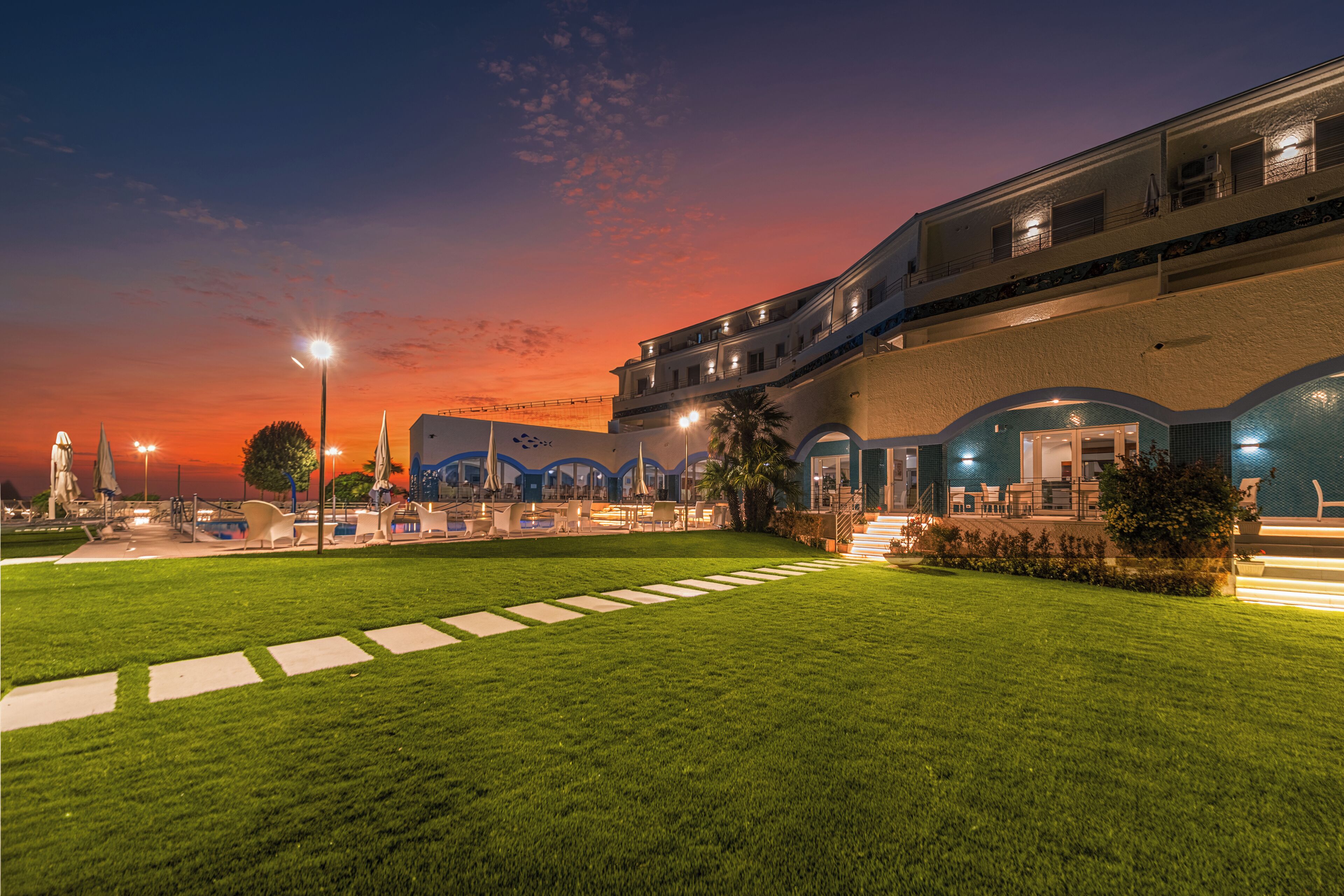 Un hôtel doté d’une piscine, d’une pelouse bien entretenue et offrant une vue imprenable sur le coucher de soleil.