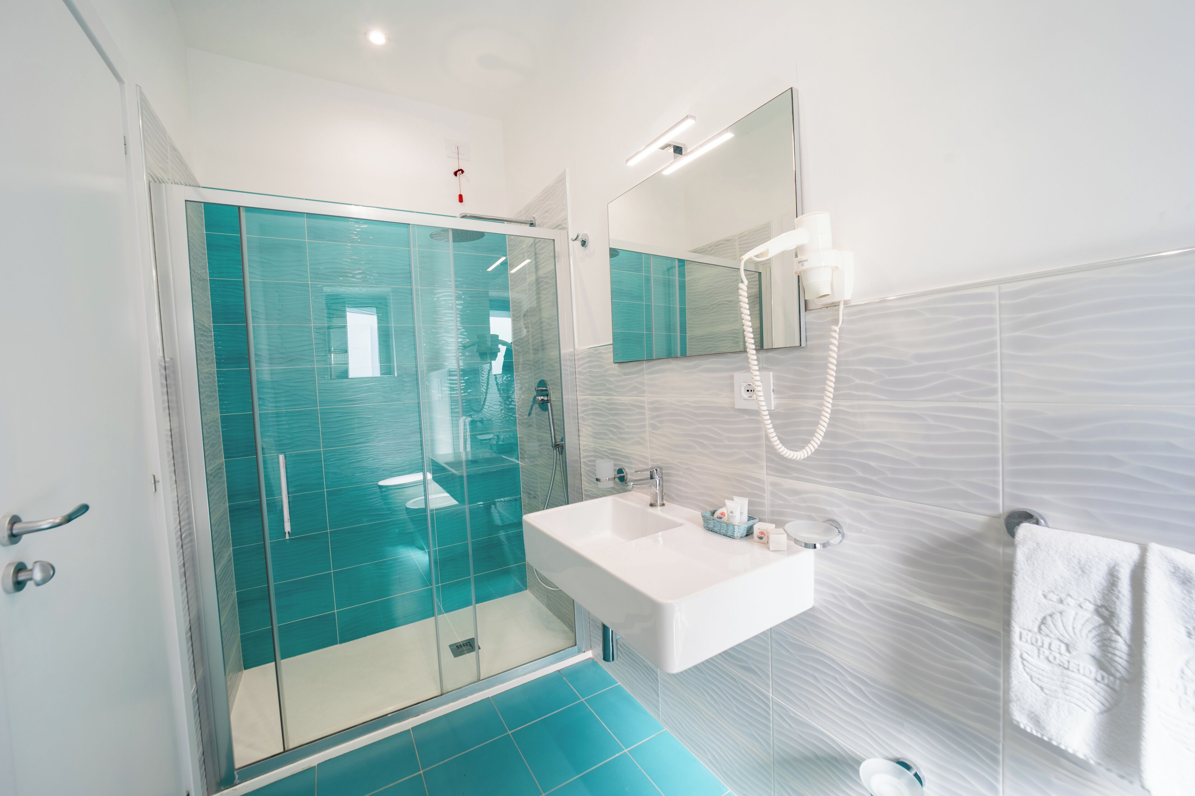 A modern bathroom with a glass-enclosed shower, a white sink, and a large mirror.