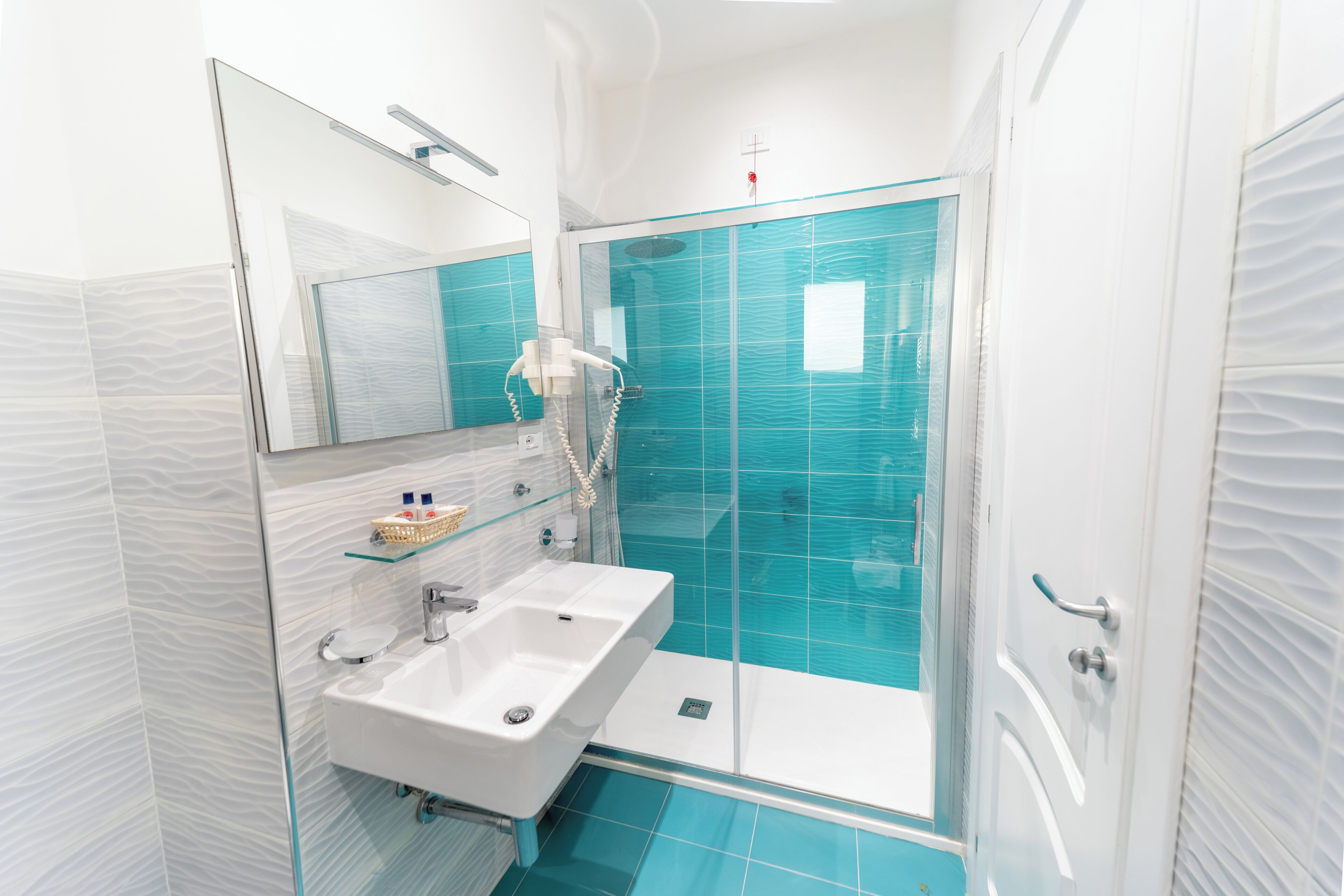 Ein modernes Badezimmer mit einer Duschkabine aus Glas, einem weißen Waschbecken und einem Spiegel darüber.