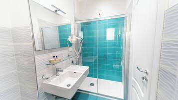 Ein modernes Badezimmer mit einer Duschkabine aus Glas, einem weißen Waschbecken und einem Spiegel darüber.