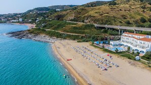 Un hotel frente al mar con playa, piscina y vistas al océano.