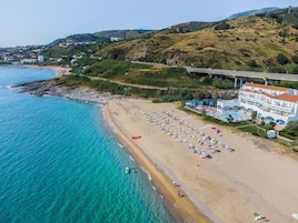 Un hotel frente al mar con playa, piscina y vistas al océano.