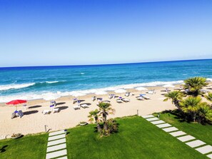 Une plage avec des parasols, des chaises longues et une vue dégagée sur l’océan.