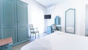 Una habitación de hotel con cama, una silla, un escritorio, un espejo y televisión.