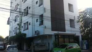 A multi-story building with a sign indicating it is a hotel. There are multiple windows, some with shutters, and a green car parked in front. - Chiang Mai Tree Hostel (Chiang Mai)