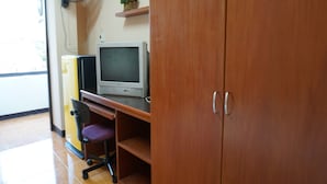 A room with a wooden cabinet, a desk with a computer monitor, a chair, and a wall-mounted fan. - Chiang Mai Tree Hostel (Chiang Mai)