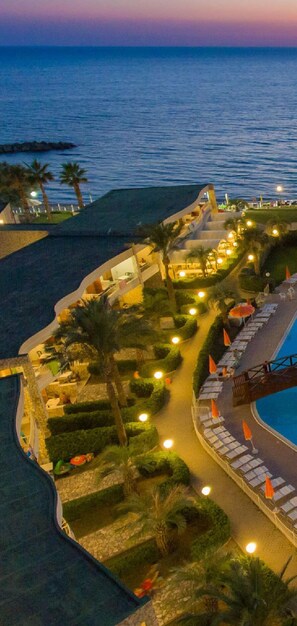 Un resort con piscina, palmeras y vista al atardecer.