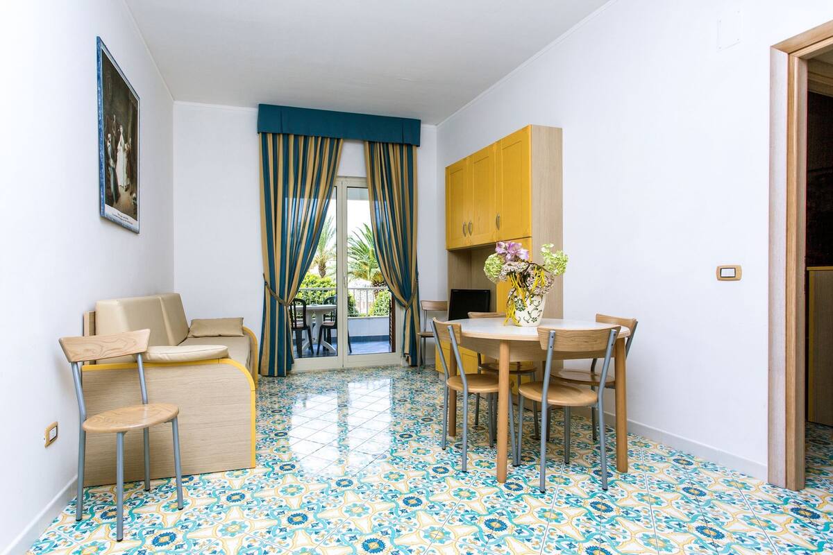 A compact room with a dining area, a sofa, and a small kitchen.