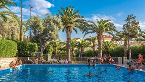 A swimming pool surrounded by palm trees and a stone wall.