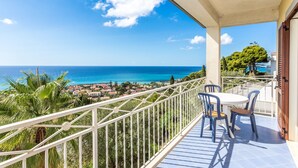 A balcony with a view of the sea and a town below.