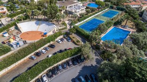 An aerial view of a resort with a tennis court, a swimming pool, and a theater.