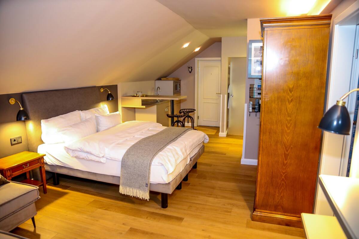 Une chambre à coucher avec un grand lit, des tables de chevet, un bureau, un miroir et une armoire.