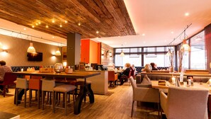 Restaurante moderno com teto de madeira, área de bar e assentos para hóspedes.