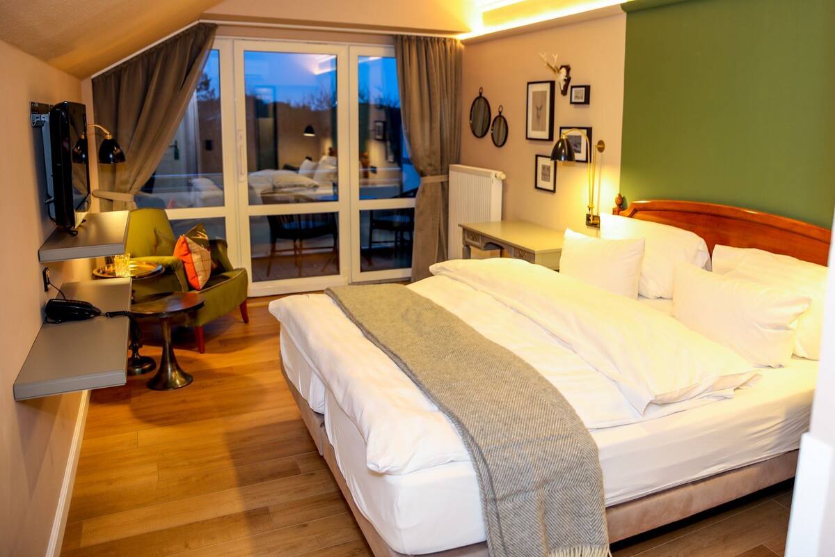 Une chambre d’hôtel équipée d’un lit, d’un bureau, d’une chaise, d’un téléphone et offrant une vue par la fenêtre.