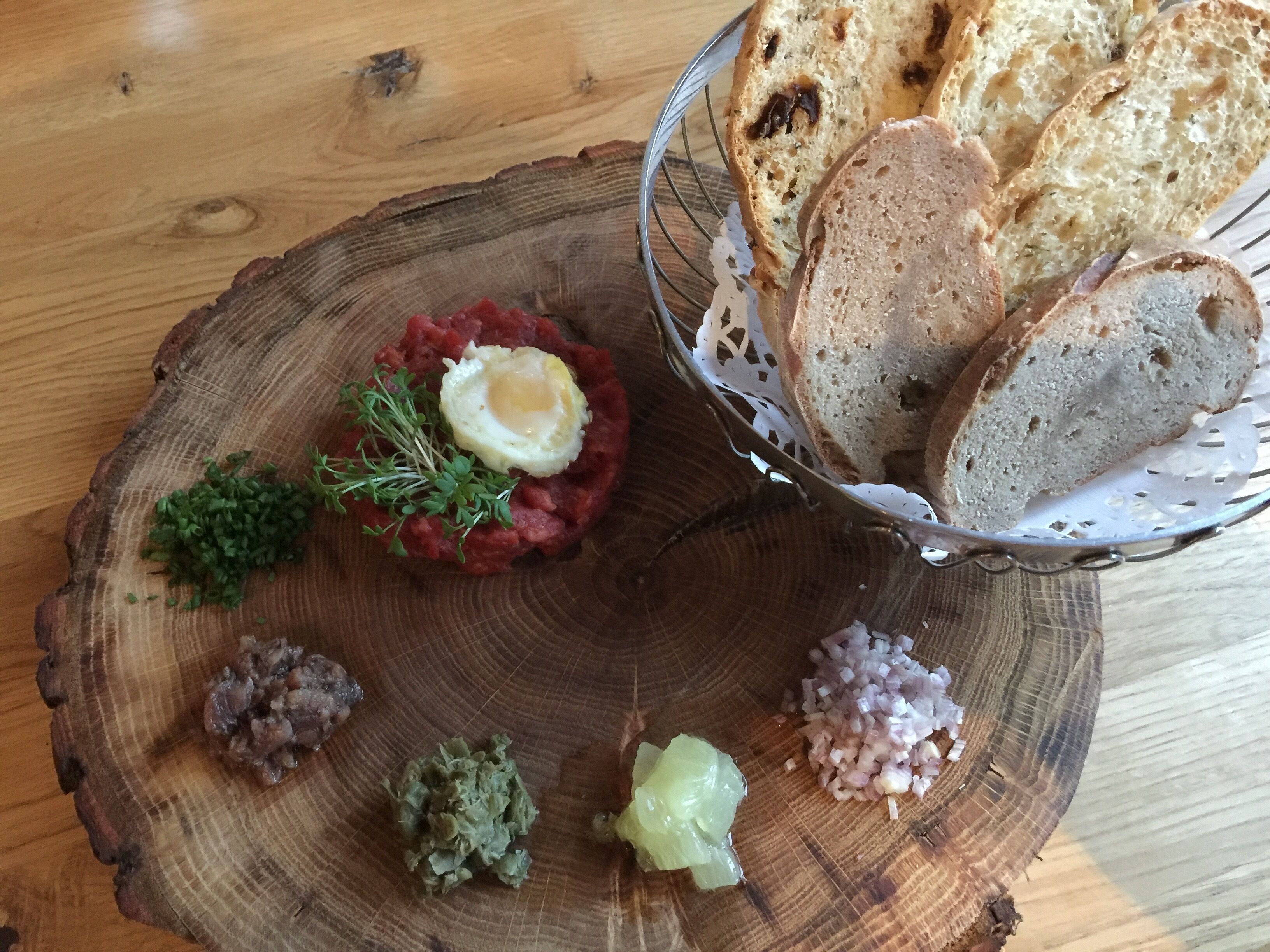 A wooden table with a rustic bread basket and a wooden serving board with various food items.