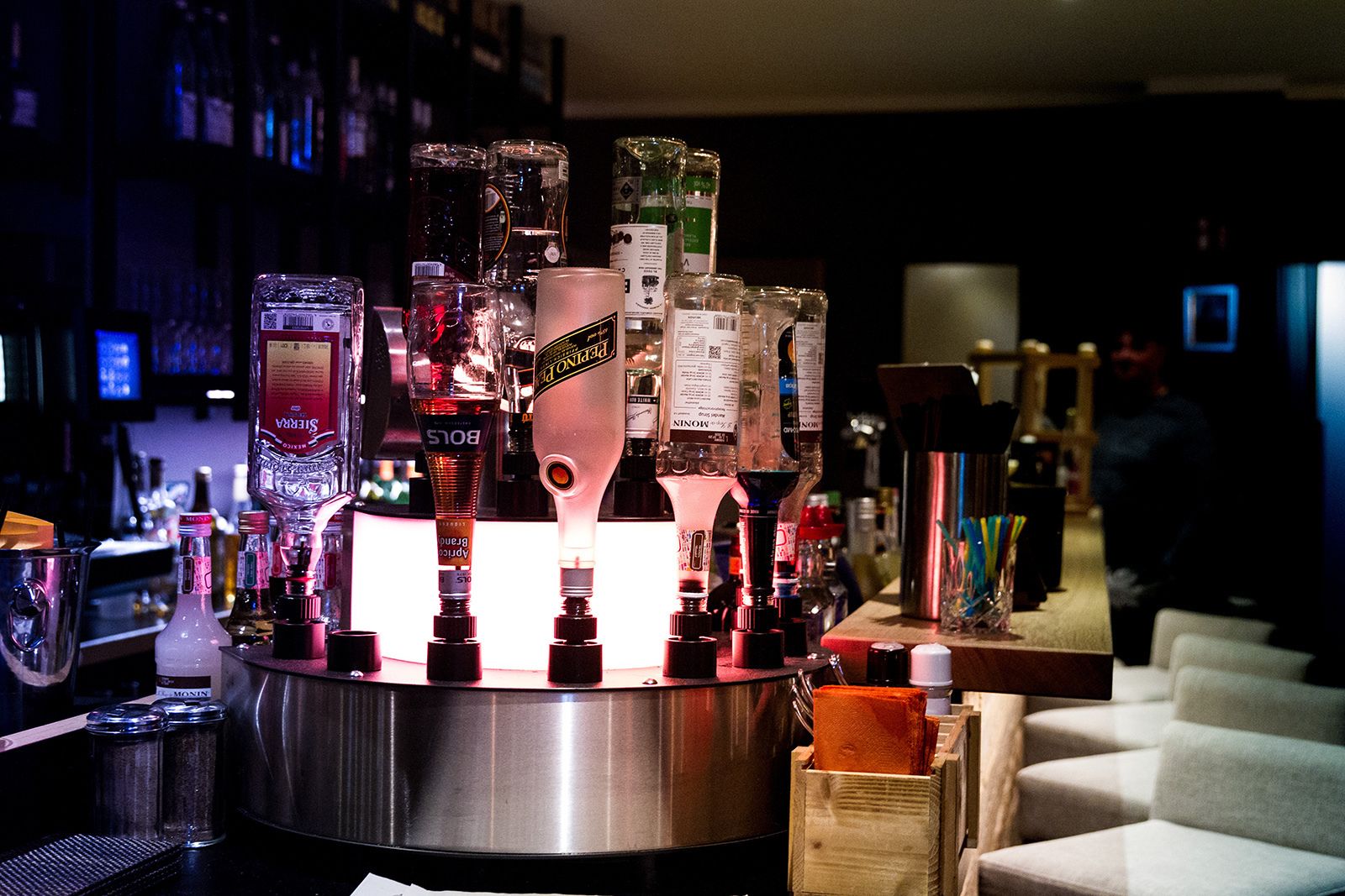 A bar area with various bottles and glasses, including a prominent bottle of Perno Pilsner beer.