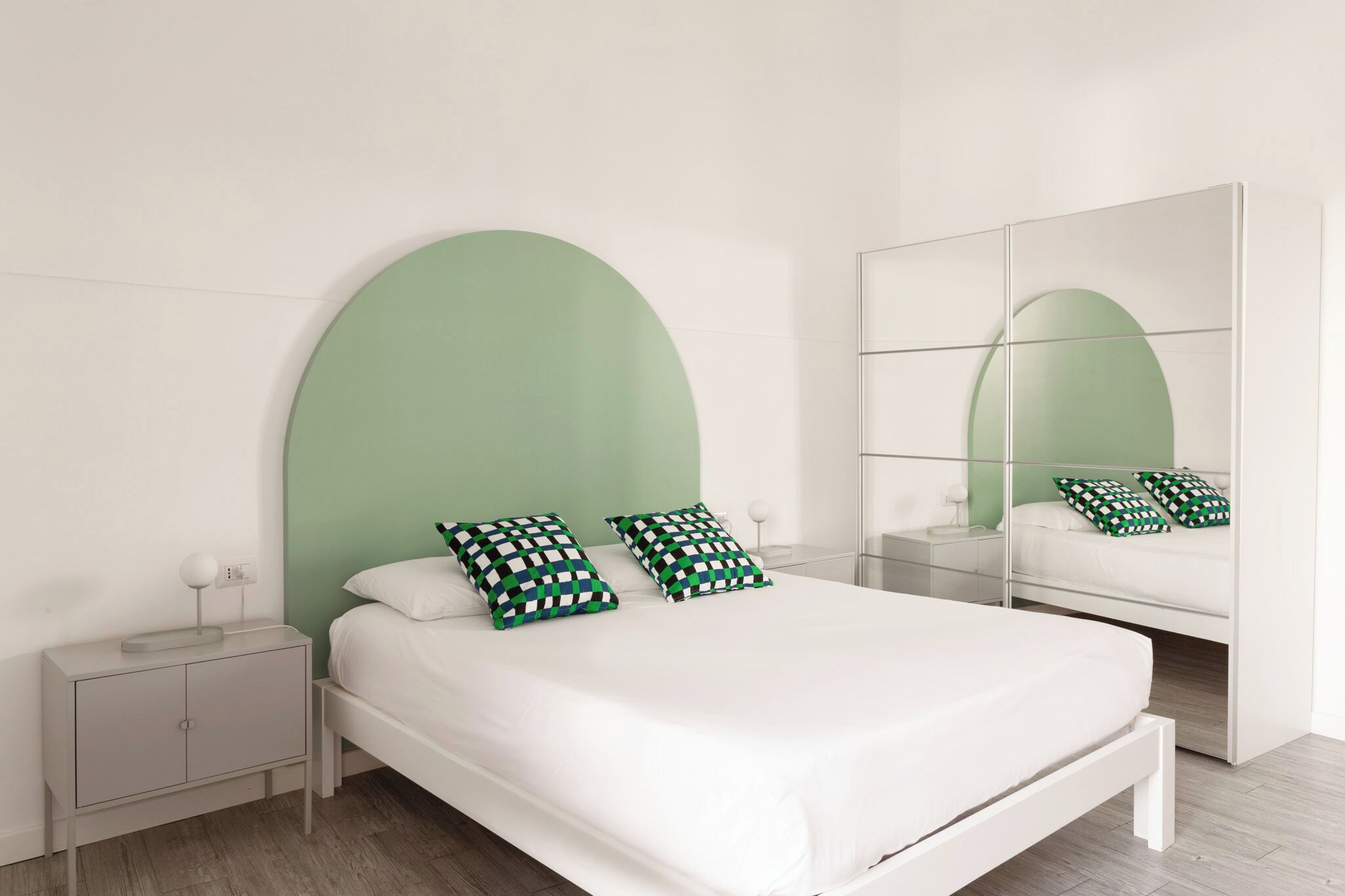 Een moderne slaapkamer met een groot bed, een nachtkastje en een spiegel.