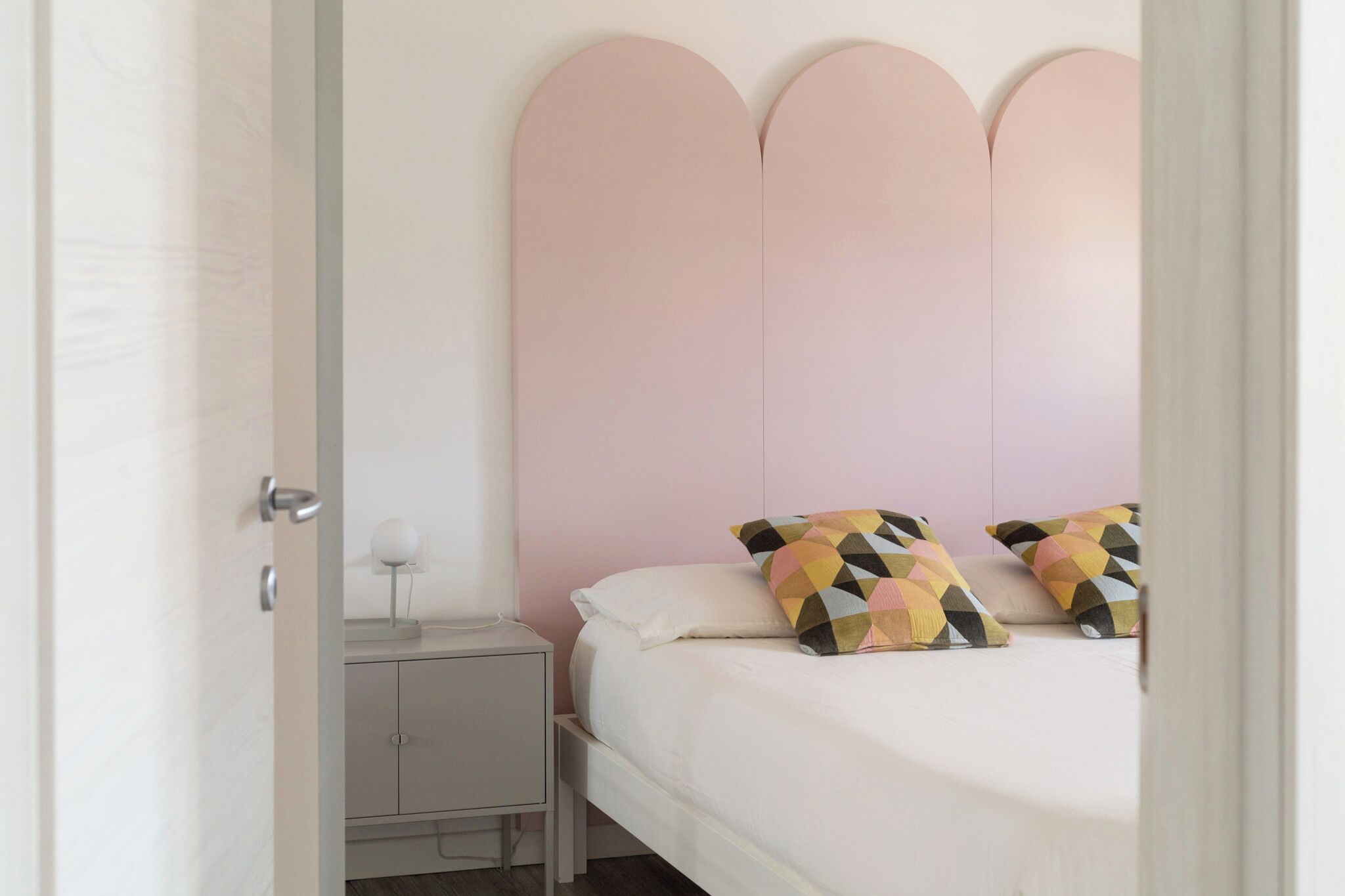 Un dormitorio con cama, mesita de noche y cabecero fijado a la pared.