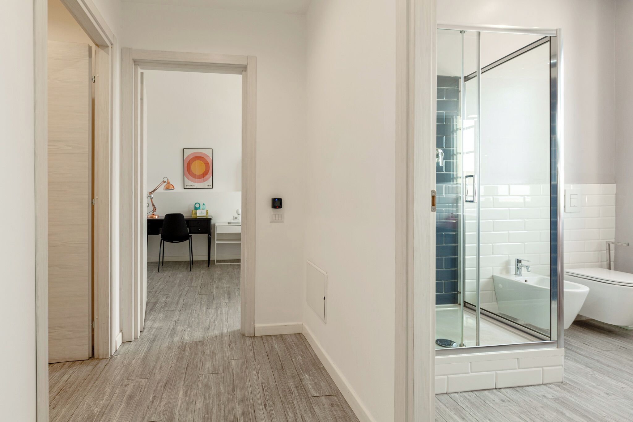 Un baño moderno con ducha envuelta en vidrio, un lavamanos blanco y un inodoro blanco.
