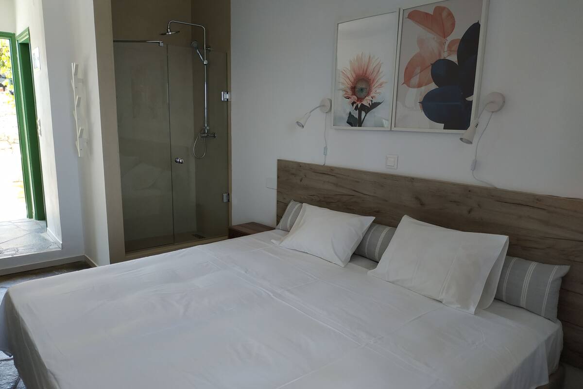 A neatly made bed with white linens, a wooden headboard, and two wall-mounted light fixtures.