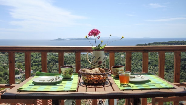 A table set outdoors with a view of the sea and hills. - Asteri Apartments (Alonissos)