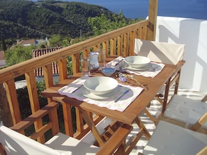 A wooden deck with a table set for two, overlooking a scenic landscape.