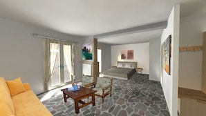 A room with a stone floor, a bed, a sofa, a table, and a window with curtains. - Asteri Apartments (Alonissos)