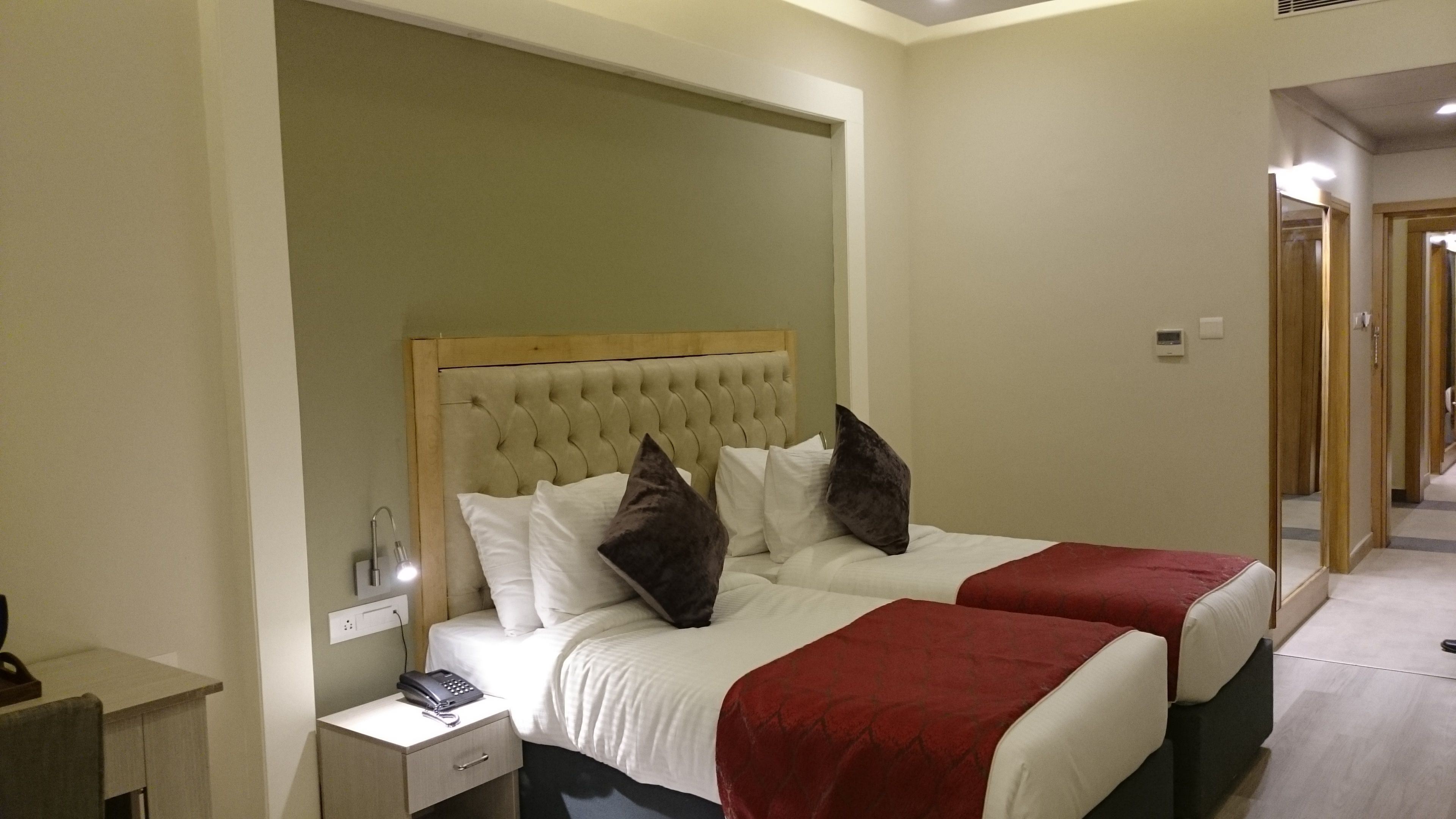 Una habitación de hotel con dos camas, una mesita de noche con lámpara y un teléfono.