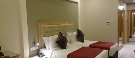 Una habitación de hotel con dos camas, una mesita de noche con lámpara y un teléfono.