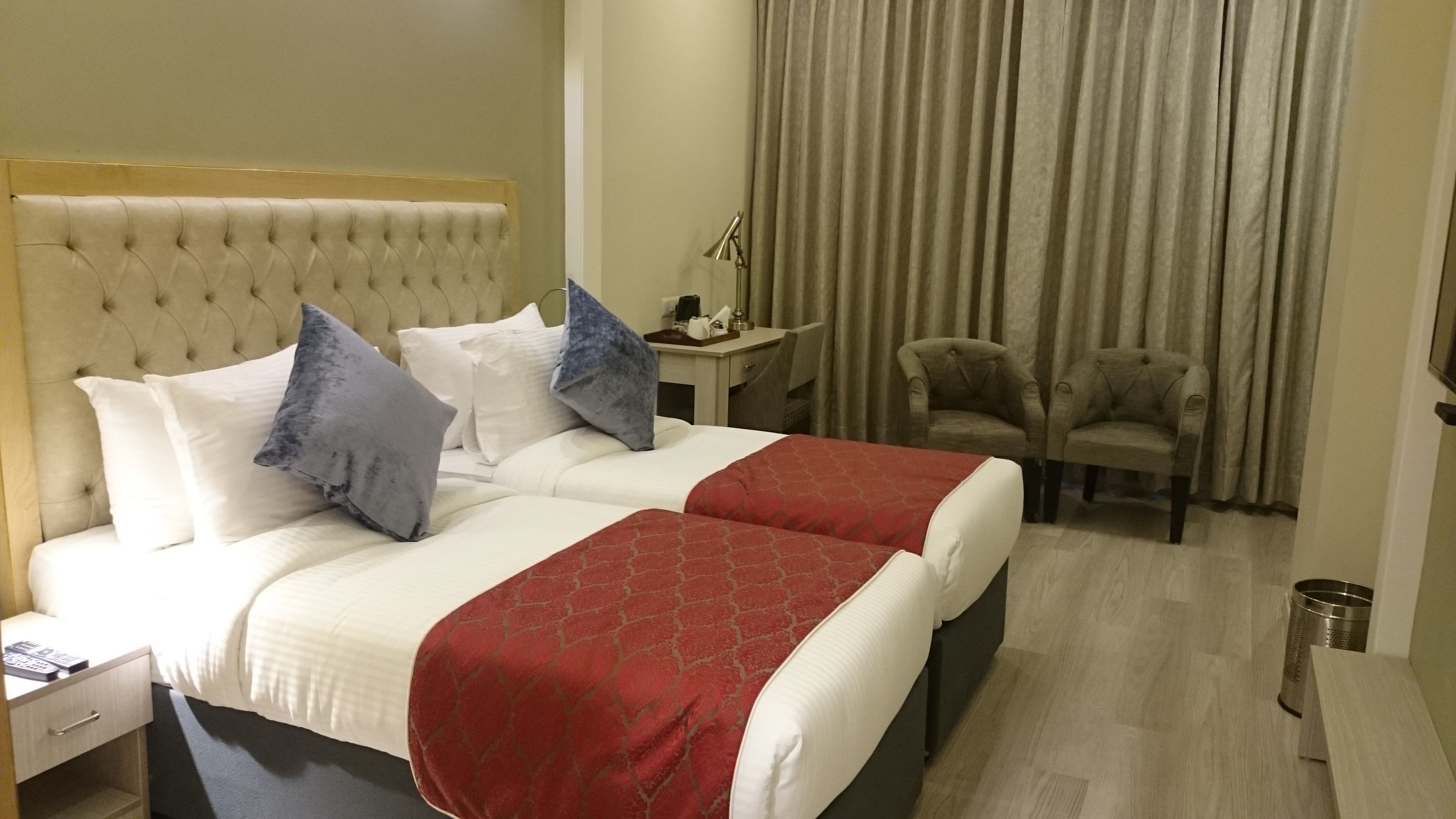 A hotel room with a large bed, two bedside tables, a desk, a chair, and a curtain.