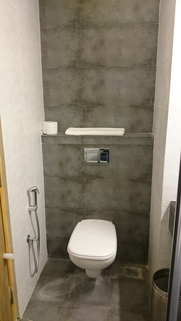Un baño pequeño y moderno con inodoro blanco, ducha y barra para toallas.