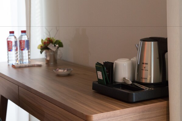 Una mesa de madera con dispensador de agua, cafetera y una pequeña planta.