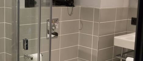 A modern bathroom with a glass shower enclosure, a white toilet, and a sink.