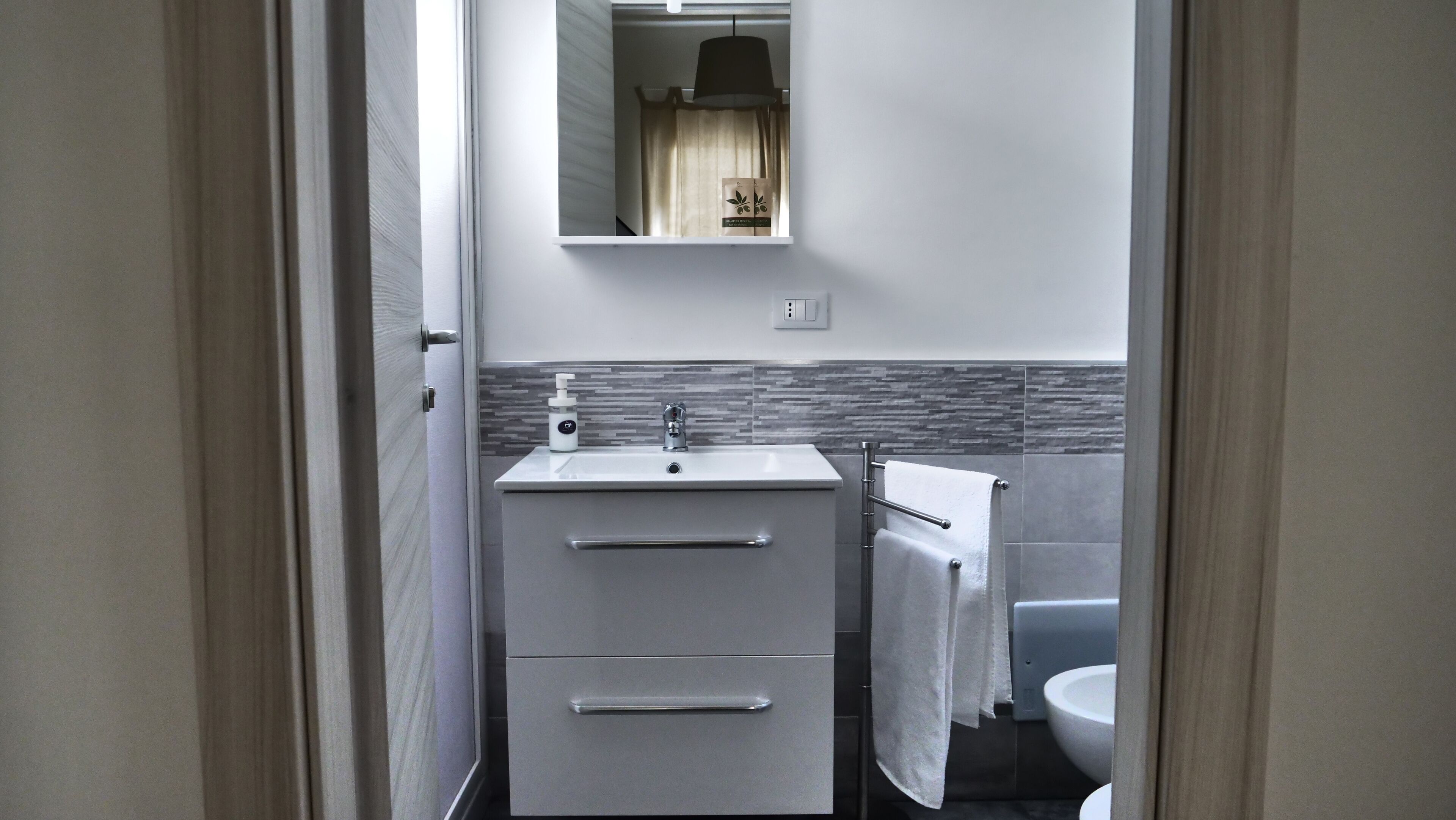 Un baño moderno con lavamanos, espejo y retrete.