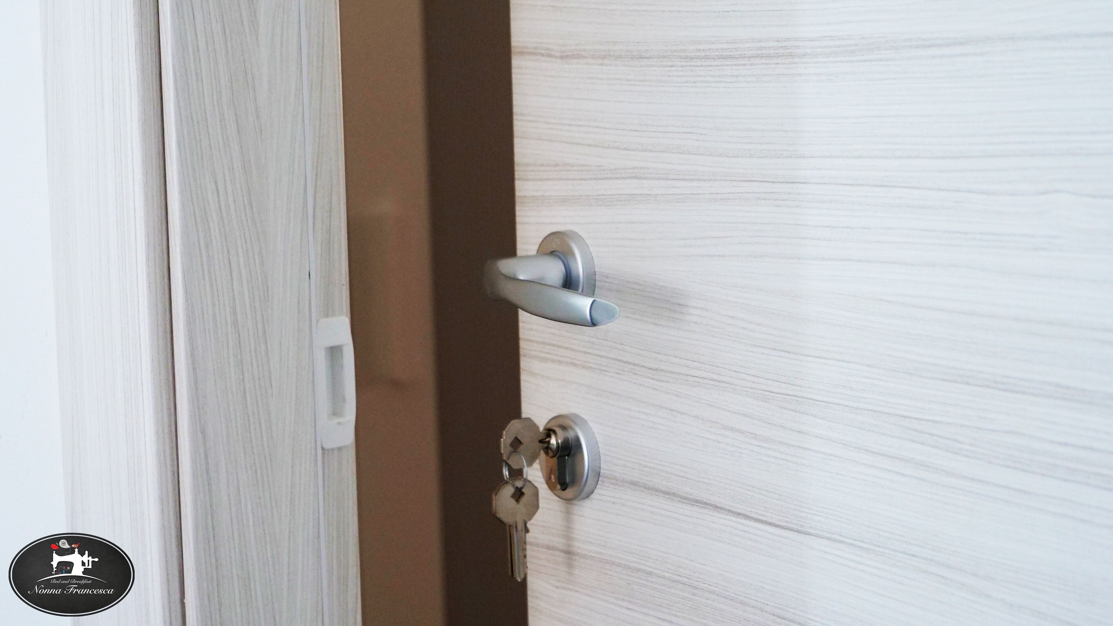 A door with a silver handle and a keyhole, and a white keychain hanging on the door.