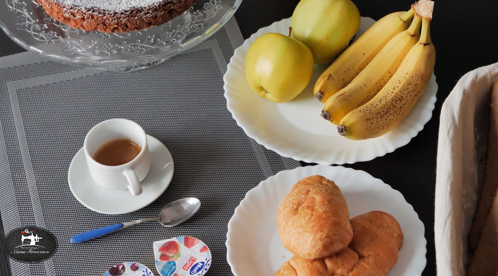 Ein Tisch mit einer Kaffeetasse, einer Bananenschale, einer Auswahl an Gebäck und einer dekorativen Platte mit Birnen.