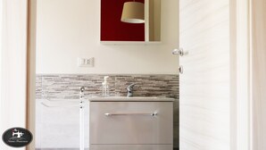 Una cocina moderna con salpicadero de azulejos, electrodomésticos de acero inoxidable y una lámpara colgante.