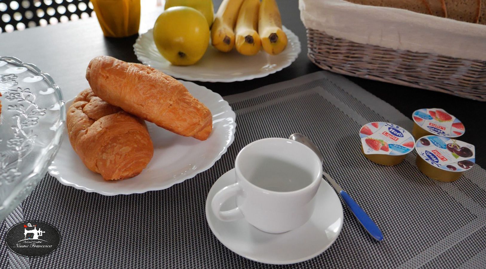 Una tavola apparecchiata con croissant, una tazza di caffè e marmellata di frutta.