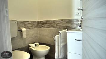 A bathroom with a toilet, bidet, and sink, all in white.