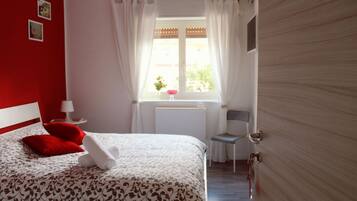 Une chambre à coucher avec un lit, une chaise, une fenêtre avec des rideaux et une porte.